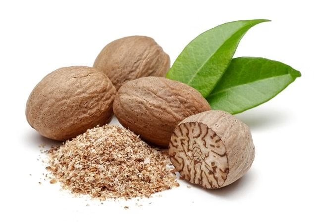 Whole Indonesian nutmeg seeds, ground nutmeg and fresh nutmeg leaves